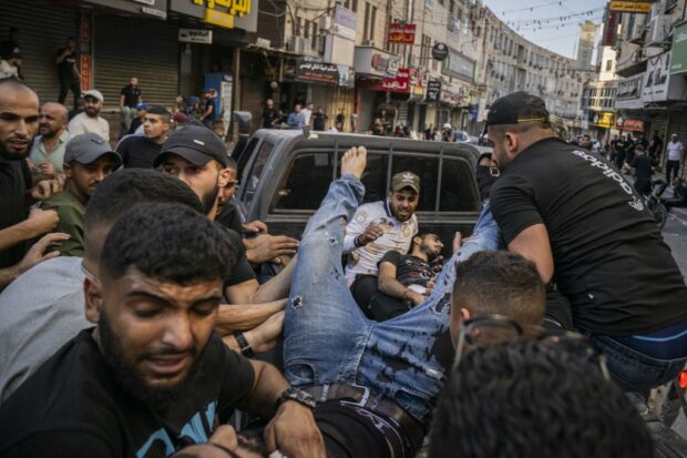 Two injured men are carried away in the back of a pick-up truck after being reportedly shot by Israeli forces during confrontations with them in the occupied West Bank city of Jenin on November 9, 2023. 