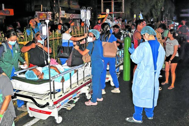 EMERGENCY Patients are evacuated out of Manuel J. Santos Hospital in Butuan City on Saturday night after a magnitude 7.4 earthquake caused a part of the hospital building to catch fire, engulfing the vicinity with smoke. —PHOTOS BY ERWIN MASCARIÑAS