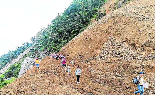 RISKY ROUTE Stranded individuals walk past the landslide-hit Manila North Road traversing Barangay Pancian in Pagudpud, Ilocos Norte on Sunday. The road has been closed to motorists for safety reasons due to rain-induced avalanche. PHOTO COURTESY OF THE DEPARTMENT OF PUBLIC WORKS AND HIGHWAYS 