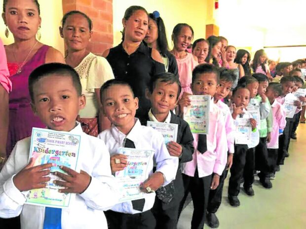 MILESTONE Badjao and Sama preschool children pose with their parents just before the moving up ceremony in 2018 in what was then the Bihing Tahik Primary School. Going on to the next education ladder has been a life-changing journey for the Badjao and Sama families of Barangay Rio Hondo. 