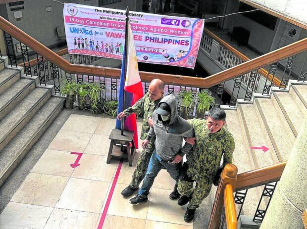 A man who later turned out to be a police “patrolman” is escorted out of the Baguio City Hall of Justice on Thursday morning after being caught secretly taking videos and photos of activists who were in the building for a hearing.