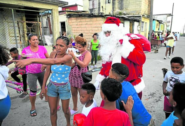 In Cuba, a man also dressed as Santa Claus walks with children through the streets of Havana last Thursday. 
