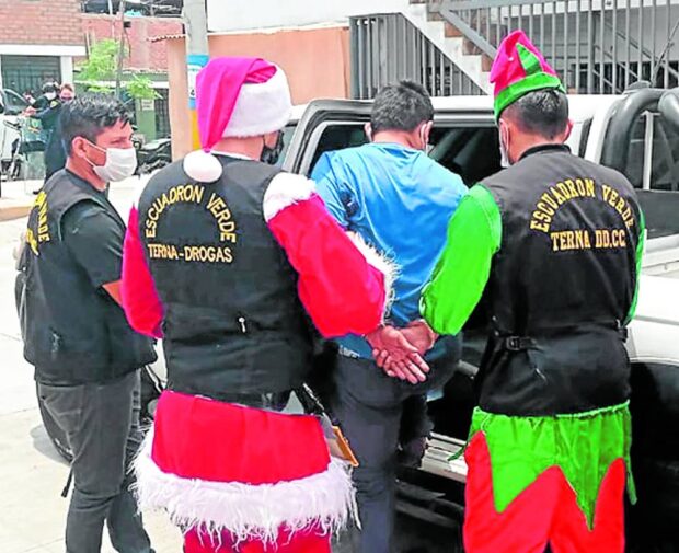 A police agent dressed as Santa Claus leads his squad in the arrest of a drug dealer in a dangerous neighborhood in Lima, Peru. 