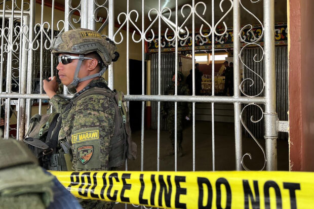 Military troops stand guard at the entrance of Dimaporo Gymnasium while police investigators look for evidence after a bomb attack at Mindanao State University in Marawi, Lanao del sur province on Dec. 3, 2023. 
