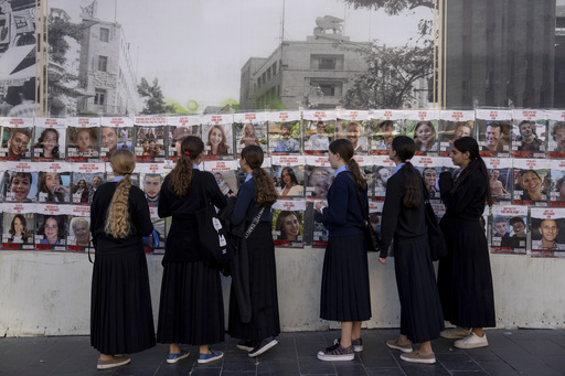 Women look at photos of Israelis missing and held captive in Gaza, in downtown Jerusalem, Sunday, Dec. 3, 2023. Hamas militants kidnapped about 240 people in an Oct. 7 attack and released over 100 of them during a weeklong cease-fire that ended on Friday. (AP Photo/Ohad Zwigenberg)