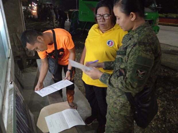 Pablita Casanoza (center), on Dec. 27, 2023, goes over the set of documents needed to claim the remains of her brother, Joedil Virtudazo, a New People’s Army leader killed in a clash with Army troops in Tagbina, Surigao del Sur, on Dec. 26.