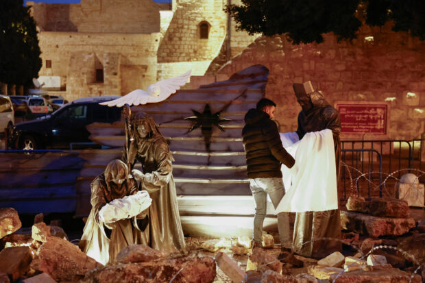 The figures of a Christmas installation amid rubble surrounded by a razor wire are unveiled on Manger Square in Bethlehem