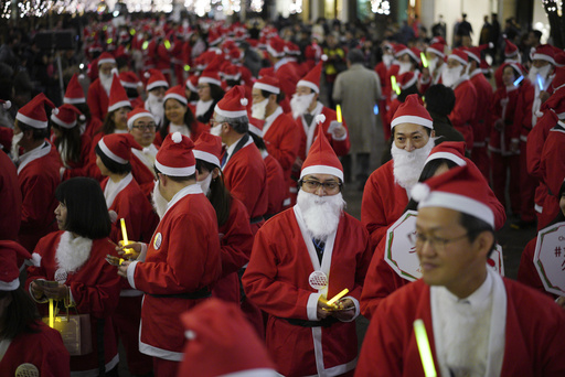 FILE - Approximately 200 local employees dressed in Santa Claus costumes parade in the festive atmosphere through the Marunouchi district in Tokyo, Friday, Dec. 22, 2017. (AP Photo/Eugene Hoshiko, File)