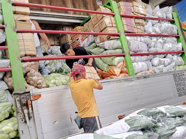 In this photo taken in April 2023, workers at the vegetable trading post in La Trinidad, Benguet, keep up with the arrival of delivery trucks unloading freshly harvested vegetables from farms in the province and other areas in the Cordillera region.