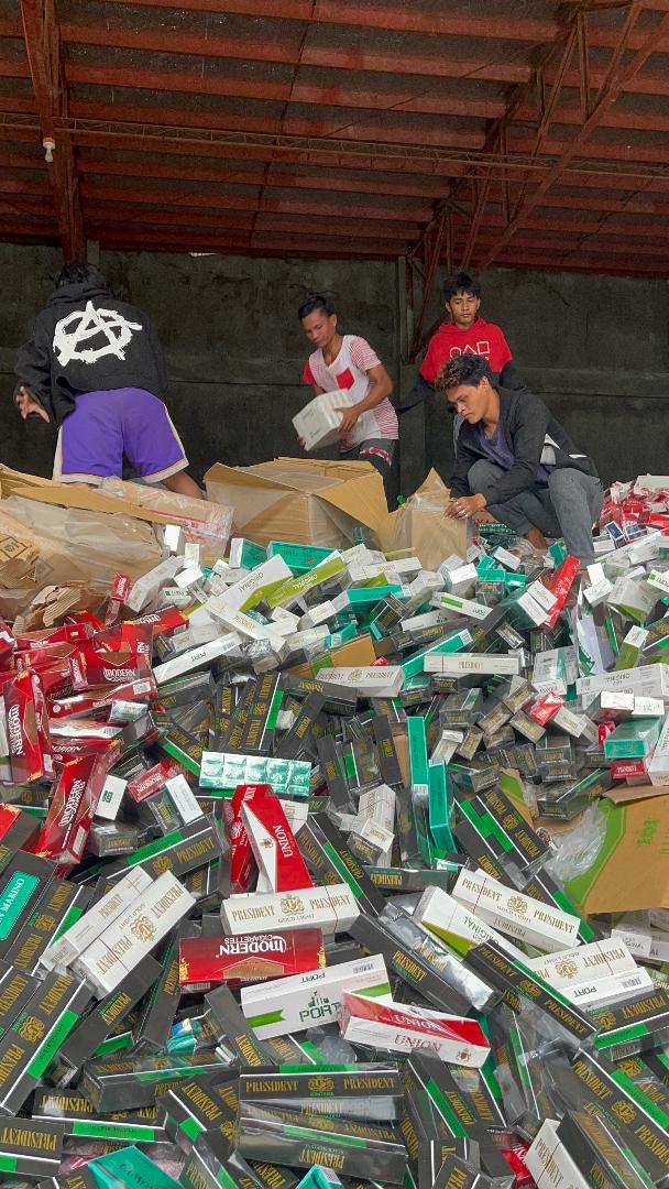 Laborers unbox thousands of master cases of contraband cigarettes in a warehouse in Zamboanga City.