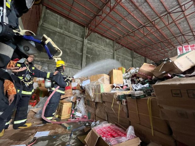 Personnel from the Bureau of Fire Protection drench all the boxes of smuggled cigarettes as part of the process of condemning the contraband items.