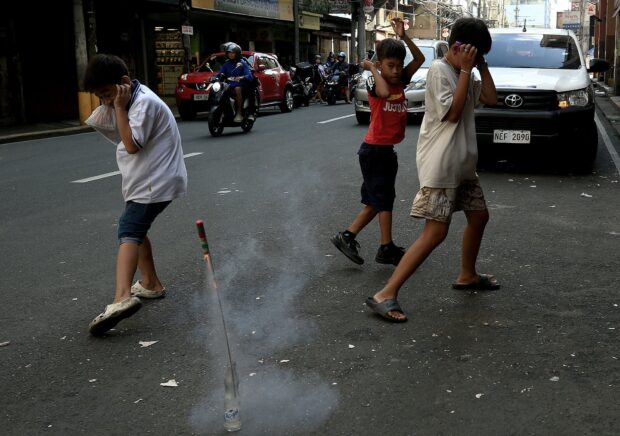 Children light firecrackers at Juan Luna Street in Manila on New Year’s Eve 2023.