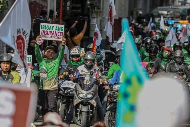 Food delivery riders, supported by the National Union of Food Delivery Riders, rally in Quezon City against Grab's new fare matrix that slashes their earnings.
