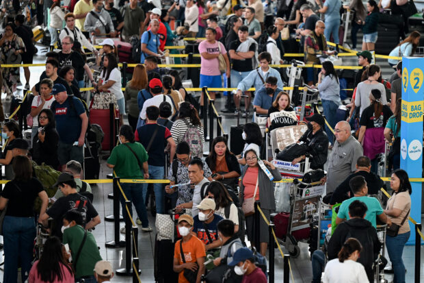 People queue at the check-in counters at Ninoy Aquino International Airport in Pasay, Metro Manila on December 22, 2023, ahead of Christmas celebrations. (Photo by JAM STA ROSA / AFP)