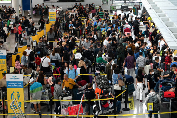 People queue at the check-in counters at Ninoy Aquino International Airport in Pasay, Metro Manila on December 22, 2023, ahead of Christmas celebrations. (Photo by JAM STA ROSA / AFP)