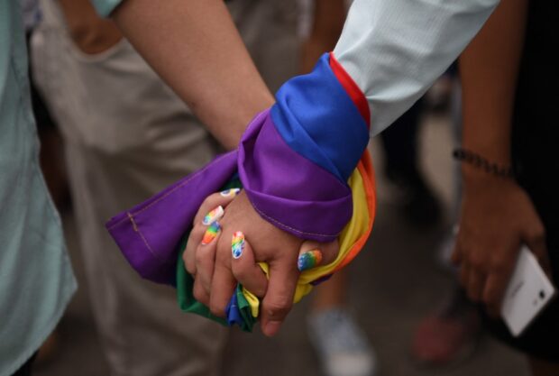 A couple holds hands wrapped in a rainbow flag as thousands of Lesbian Gay Bisexual Transgender/Transexual Queer (LGBTQ) members hold a pride march at a sports complex in Marikina City in this file photo taken on June 30, 2018.