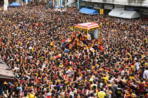 Catholic devotees jostle with each other as they try to touch a glass-covered carriage carrying the so-called Black Nazarene during an annual religious procession in Manila on January 9, 2024. Hundreds of thousands of Catholic faithful swarmed a historic statue of Jesus Christ as it was pulled through the streets of the Philippine capital on January 9, in one of the world's biggest displays of religious devotion.Ted ALJIBE / AFP