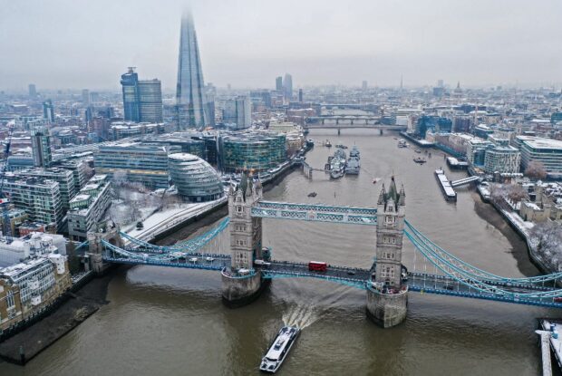 (FILES) An aerial view shows snow-covered offices and buildings including the Shard skyscraper, as a boat passes under Tower Bridge on the River Thames, from Wapping, east London on December 12, 2022. Australian-born private equity entrepreneur Angus Murray has submitted the proposal to transform the history-rich yet little-known Kingsway Exchange Tunnels into a major tourist attraction. (Photo by Daniel LEAL / AFP)