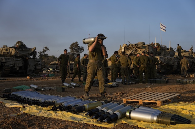 Israeli soldiers load shells onto a tank at a staging area in southern Israel near the border with Gaza on Sunday, Dec. 31, 2023.