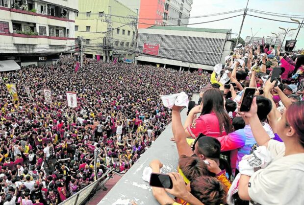 Devotees and onlookers alike view the crowd from the balcony of a building at the corner of Carlos Palanca Street and Quezon Boulevard in Manila’s Quiapo district.