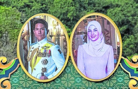 ‘LIKE A FAIRY TALE’ The portraits of Prince Abdul Mateen and his bride Anisha Rosnah appear on a billboard in Brunei ahead of their wedding on Thursday. —AFP