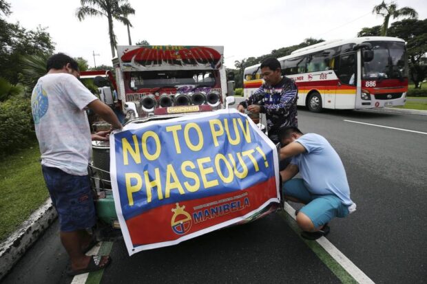 OCTOBER 16, 2023 (20231016lr2)Jeepney drivers tie a "NO to PUV Phaseout" poster on one of several jeepneys on the first day of a transport strike led by Manibela. The assembly point for the protest caravan was held along the university ave. of UP Diliman, Quezon City. LYN RILLON/PHILIPPINE DAILY INQUIRER