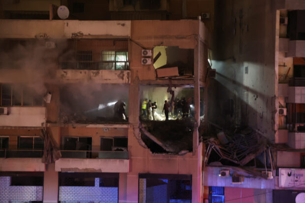 People stand at a damaged building following an explosion at Beirut suburb of Dahiyeh