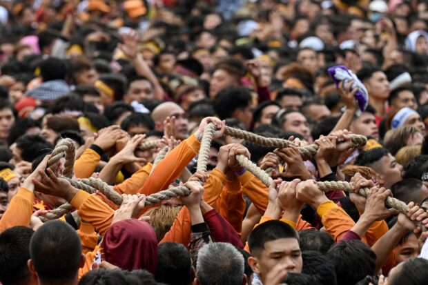Catholic devotees hold the rope attached to a glass-covered carriage carrying the so-called Black Nazarene statue during an annual religious procession in Manila on January 9, 2024. However the rope pulling the carriage unexpectedly snapped.