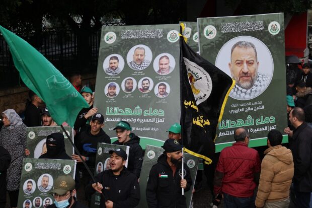 People carry portraits of Hamas' deputy leader, Saleh al-Aruri, killed and other officials killed