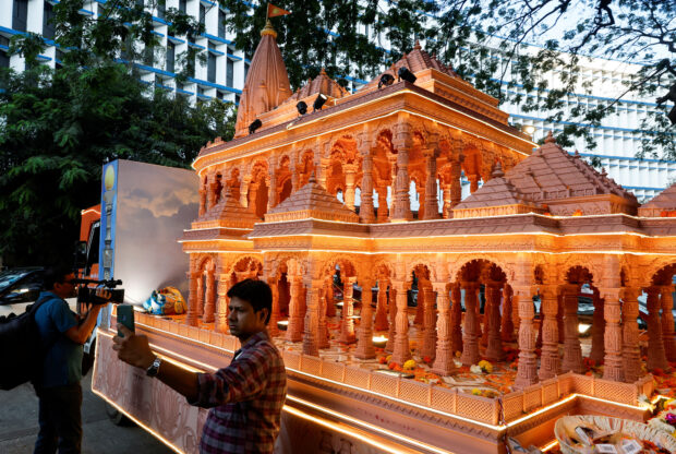 FILE PHOTO: A man takes a selfie with a replica of the Ram Mandir outside the BJP headquarters in Mumbai