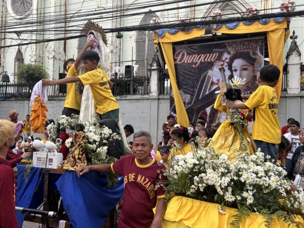 Felicisimo Bonzo, 65-year-old leader of the Balic Balic - Holy Trinity chapter, poses with his great-grandchildren who are sitting beside their replica of the Black Nazarene. 