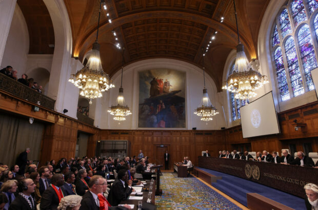 People sit inside the International Court of Justice (ICJ) on the day of the trial to hear a request for emergency measures by South Africa, who asked the court to order Israel to stop its military actions in Gaza, in The Hague