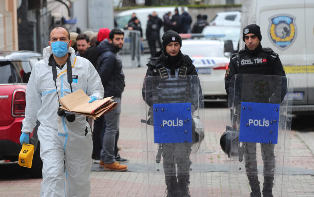 A police forensic expert examines as Turkish police stand guard outside the Santa Maria Catholic Church in Istanbul