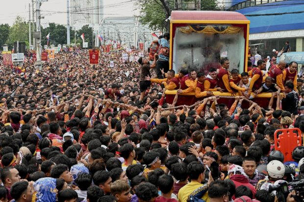 Catholic devotees jostle with each other as they try to touch a glass-covered carriage carrying the Black Nazarene during an annual religious procession in Manila on January 9, 2024.