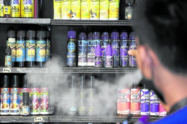 SMOKE SHOP A store helper arranges products at a vape shop in Quezon City in this 2022 photo. The Department of Trade and Industry has intensified its efforts against illegal vape sellers, issuing notices of violations and show cause orders to 269 stores as of January. —GRIG C. MONTEGRANDE 