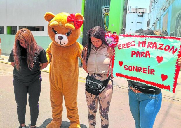 A police officer dressed as a teddy bear poses with two alleged drug dealers arrested in northern Lima on Valentine's Day. 