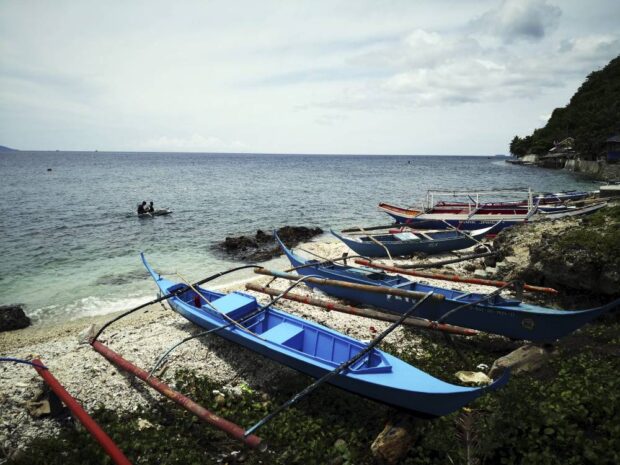 PHOTO: Fishing boats on a rocky part of a shoreline in Barangay San Andres on Verde Island in Batangas City STORY: Group estimates 2023 Mindoro oil spill damage at P41.2B