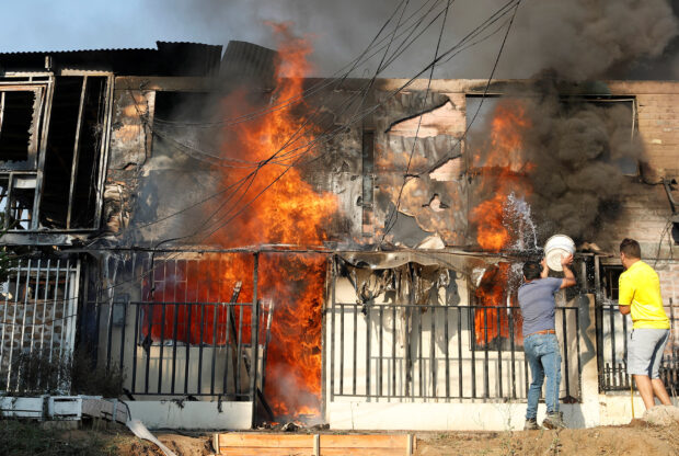 People try to extinguish a fire burning a house during the spread of wildfires in Vina del Mar