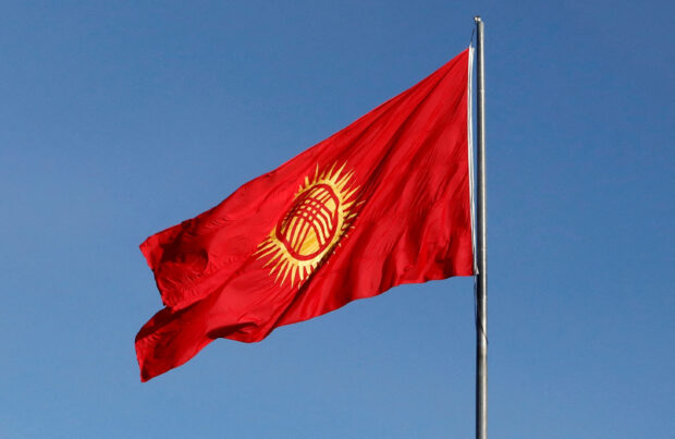Honour guards march near the renewed Kyrgyz national flag during a ceremony in Bishkek