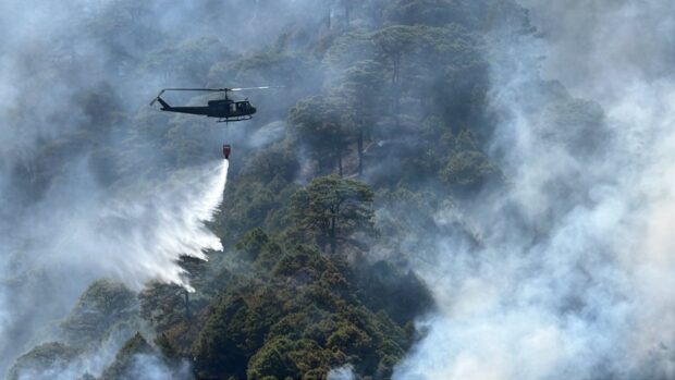 PHOTO: A helicopter of the Philippine Air Force Tactical Operations Group (PAF TOG) 1, stationed in Baguio City, airlifts a water bucket to help douse a forest fire in Itogon, Benguet, in this photo taken on Jan. 27, 2024. STORY: Benguet Rep. Yap seeks inquiry into government readiness vs forest fires