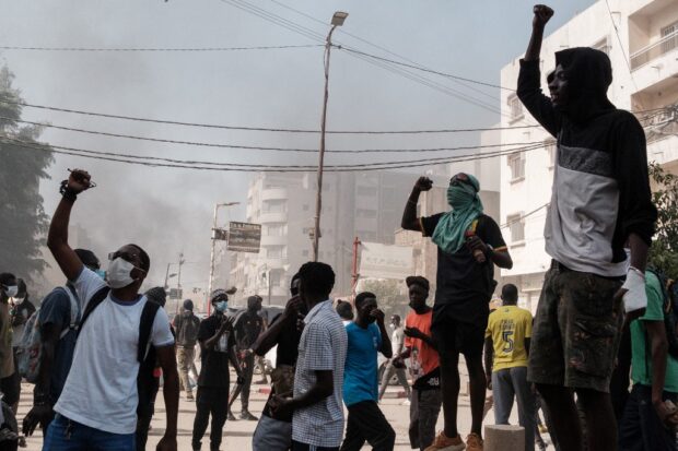 Protesters shout slogans during clashes with police on the sidelines of a protest against a last-minute delay of presidential elections in Dakar