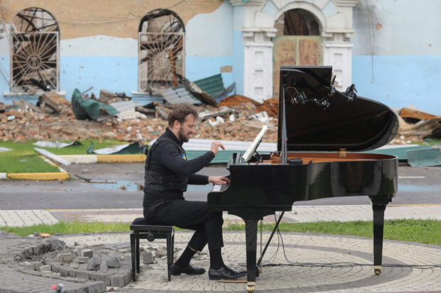 Lithuanian musician Darius Mazintas plays a piano in front of the Central House of Culture destroyed during Russia's invasion, in the town of Irpin, outside Kyiv, Ukraine 
