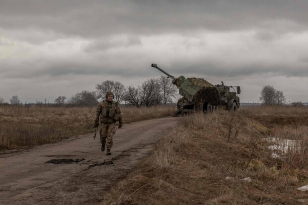 A Ukrainian soldier walks next to a howitzer while waiting for it to fire toward Russian positions, in the Donetsk region last month. 