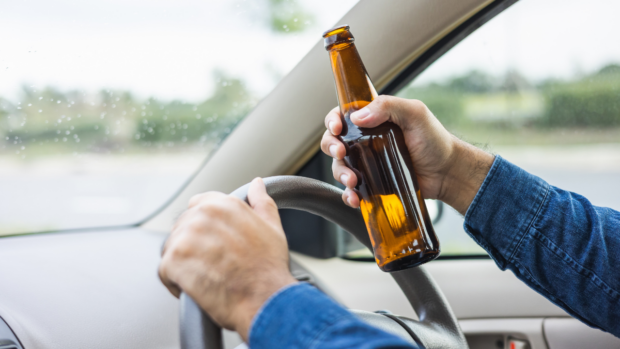 PHOTO: Stock image of driver’s left hand on car steering wheel while the right hands holds a beer bottle. STORY: Tulfo files bill seeking to impose stricter penalties for drunk drivers