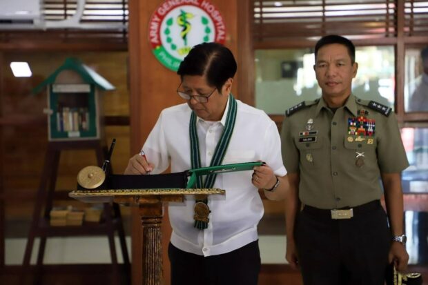 PHOTO: Ferdinand Maros Jr. signing a citation for the wounded soldiers. STORY: PHOTO: Ferdinand Marcos Jr. pins a medal on a wounded soldiers. STORY: Marcos honors 4 soldiers wounded in clash with terrorists