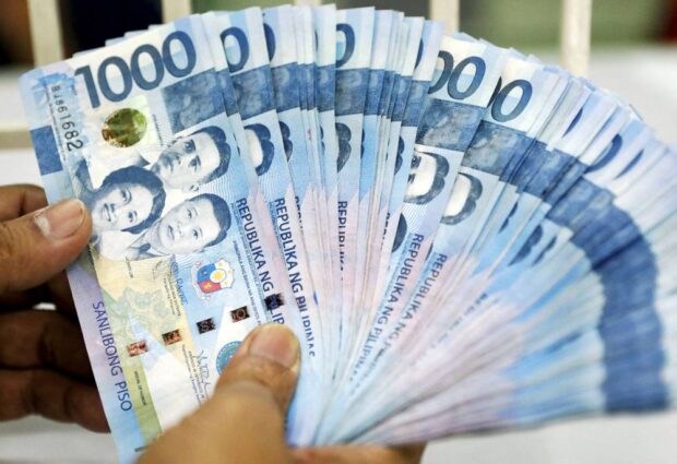 PHOTO: Hand holding fanned out 1,000-peso bills STORY: Study shows more Filipinos ditching cash transactions
