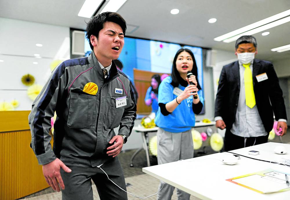 An employee of EXEO Group Inc. reacts as he tries a “perionoid,” a device that releases electrical stimulation  men menstrual japan