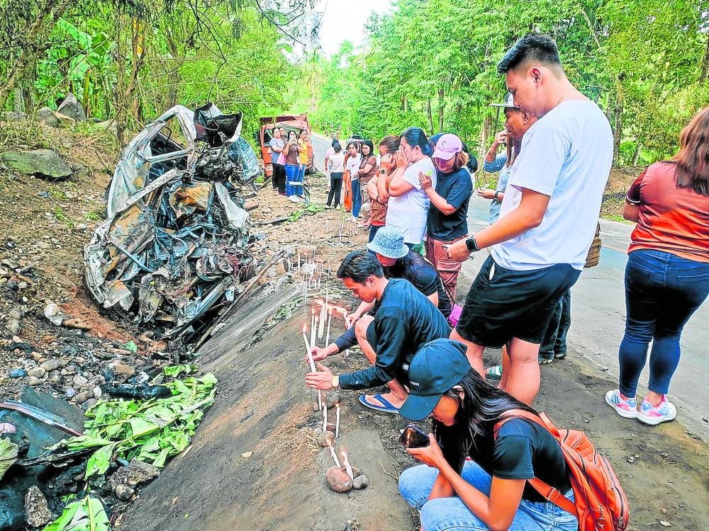 Relatives and employees of the municipality of Antipas, Cotabato, on Tuesday light candles at the site in the town where 17 people perished in a road mishap on Monday.