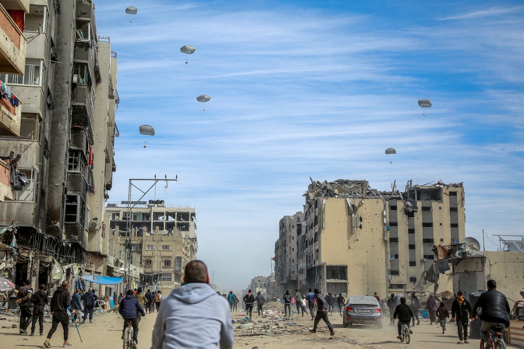 Palestinians run along a street as humanitarian aid is airdropped in Gaza City 