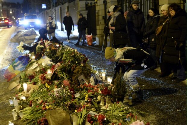 Pessoas colocam flores e velas em um memorial improvisado ao falecido líder da oposição russa Alexei Navalny em frente à antiga embaixada russa em Helsinque, Finlândia 